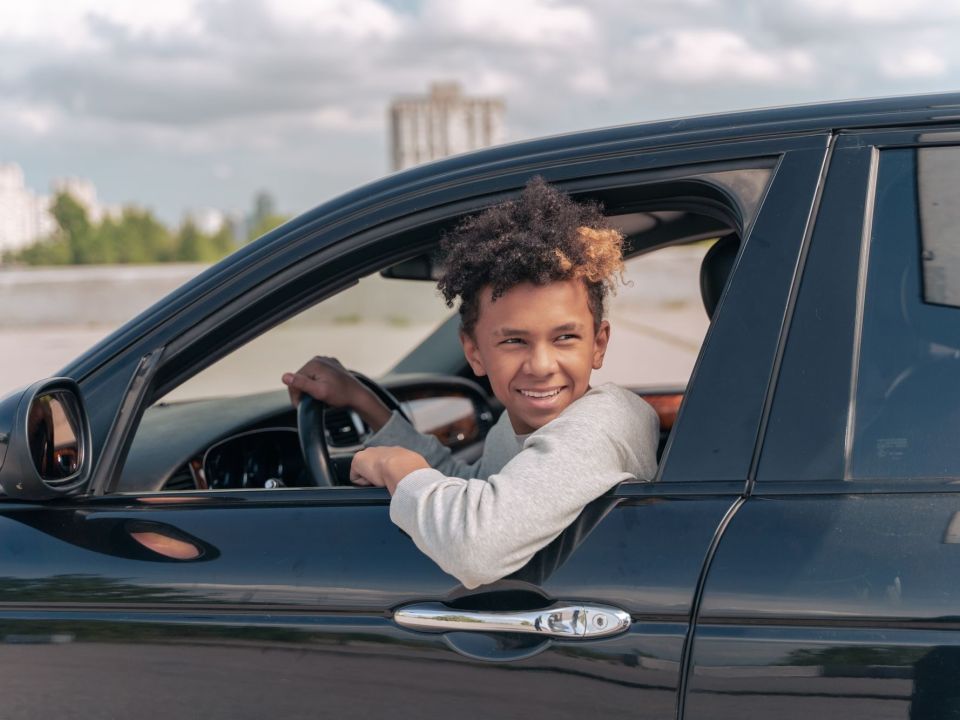 Lächelnder Jugendlicher am Steuer eines Autos