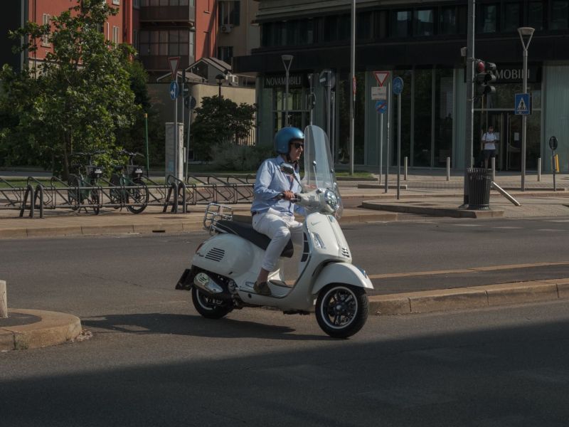 Rollerfahrer mit Helm auf einem 125er-Roller in der Stadt