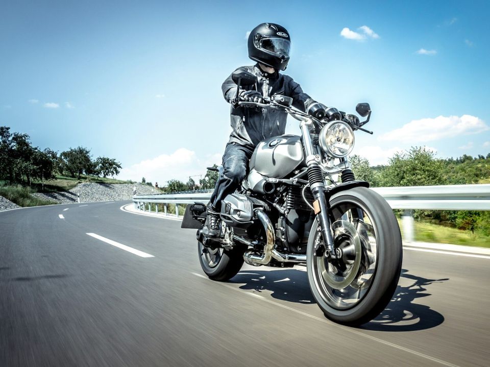 Motorradfahrer mit Helm und Schutzkleidung auf einer Landstraße